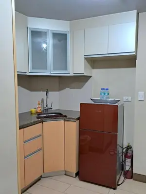 a kitchen with white cabinets and a sink and a refrigerator at NAIA Terminal 3 Condotel by Ann in Manila