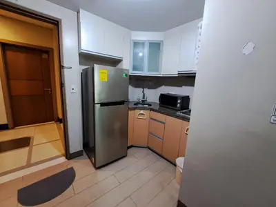 a kitchen with a stainless steel refrigerator and wooden cabinets at NAIA Terminal 3 Condotel by Ann in Manila