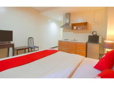 a room with a kitchen and a bed with a red blanket at OYO 769 Poblacion Suites Polaris in Manila