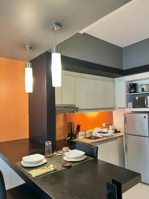 a kitchen with a counter with plates and a refrigerator at KL Serviced Residences Managed by HII in Manila