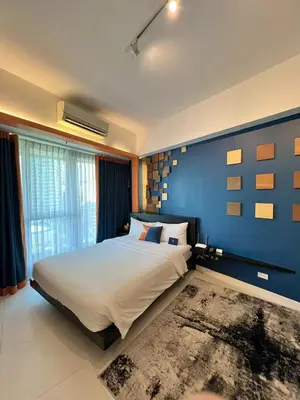 a bedroom with a large bed with a blue wall at KL Serviced Residences Managed by HII in Manila