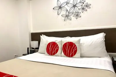 a bedroom with a bed with red and white pillows at Khotel near T3 Airport in Manila