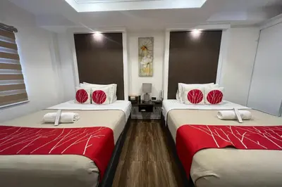 two beds in a room with red and white sheets at Khotel near T3 Airport in Manila