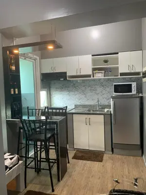 a kitchen with white cabinets and a table and chairs at Anuva Condominium with Netflix in Manila