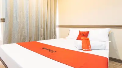 a bed with orange and white sheets and pillows at RedDoorz Plus at Canley Residential in Manila