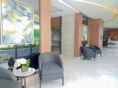 a lobby with chairs and tables and a painting at Spring Residence in Manila