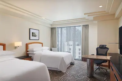 a hotel room with two beds and a desk and a window at Sheraton Manila Bay in Manila