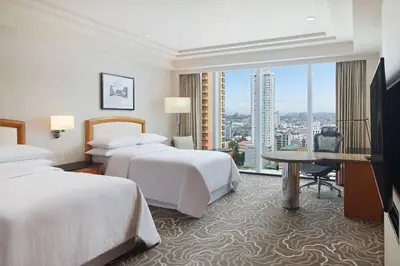 a hotel room with two beds and a desk at Sheraton Manila Bay in Manila