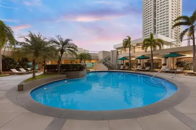 a large swimming pool with palm trees and buildings at Sheraton Manila Bay in Manila