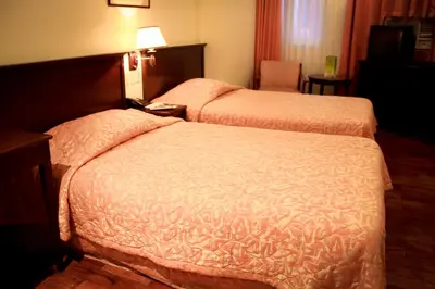 a hotel room with two beds and a chair at CityState Tower Hotel in Manila