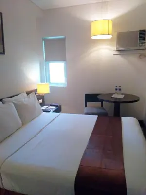 a bedroom with a large white bed and a table at CityState Tower Hotel in Manila