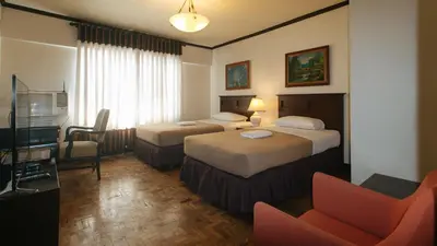a hotel room with two beds and a television at El Rico Suite Makati by RedDoorz in Manila