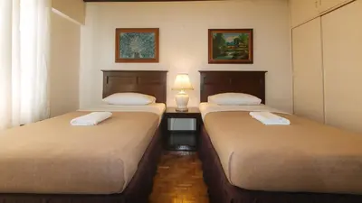 two beds in a room with a lamp on a table at El Rico Suite Makati by RedDoorz in Manila