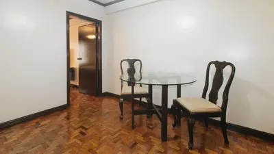 a dining room with a glass table and two chairs at El Rico Suite Makati by RedDoorz in Manila