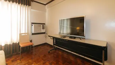 a living room with a large flat screen tv on a dresser at El Rico Suite Makati by RedDoorz in Manila