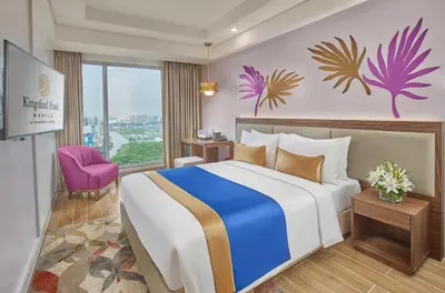 a bedroom with a large bed and a purple chair at Kingsford Hotel Manila Bay in Manila