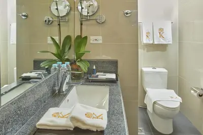 a bathroom with a sink and a toilet and a mirror at Kingsford Hotel Manila Bay in Manila