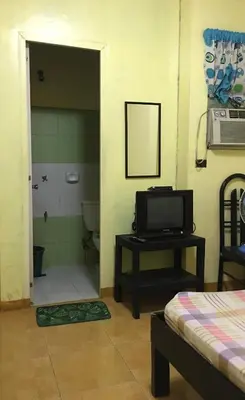 a room with a bathroom with a toilet and a television at Belen Favila Transient rooms near Airport Terminal 3 in Manila
