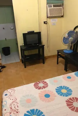 a room with a bed and a tv and a table at Belen Favila Transient rooms near Airport Terminal 3 in Manila