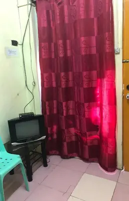 a room with a red curtain and a tv at Belen Favila Transient rooms near Airport Terminal 3 in Manila
