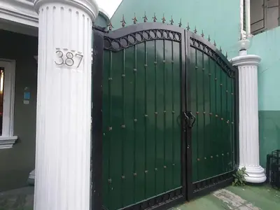 a green gate with two columns next to a house at Mint Homes in CEV Mansion in Manila