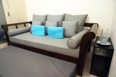 a couch with two blue pillows on it at Mint Homes in Jazz Residences Tower B in Manila