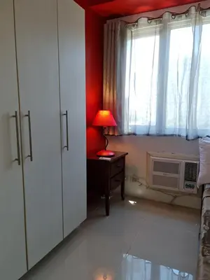 a room with a desk with a lamp and a window at Sea Residences - Condo R Us in Manila