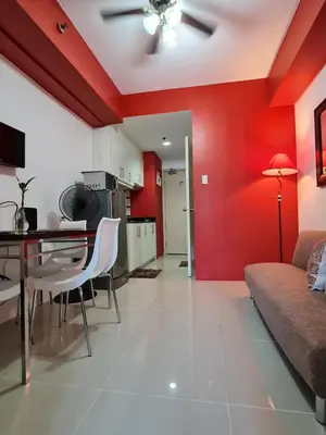 a living room with red walls and a table and a couch at Sea Residences - Condo R Us in Manila