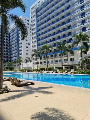 a swimming pool with chairs and a large building at Sea Residences - Condo R Us in Manila