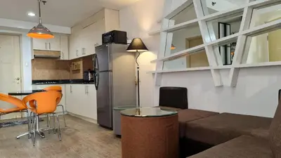 a living room with a couch and a table and a kitchen at Sea Residences - Condo R Us in Manila