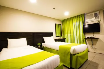 a hotel room with two beds and a television at Jade Hotel and Suites in Manila