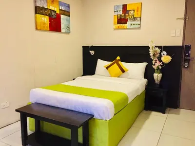 a bedroom with a green and white bed with a table at Jade Hotel and Suites in Manila