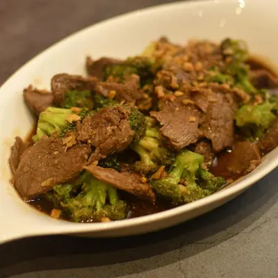 a white bowl of food with broccoli and meat at Jade Hotel and Suites in Manila
