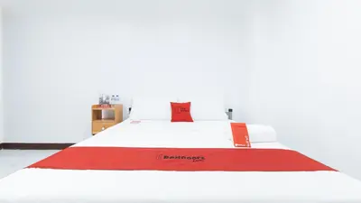 a bed with a red and white blanket on it at RedDoorz at Good 101 Paranaque in Manila