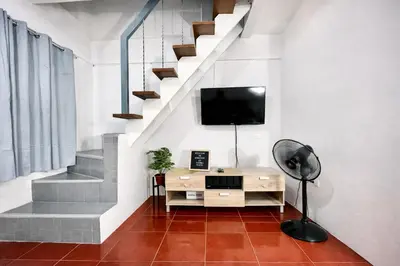a room with a desk and a tv and stairs at Transient Home at Tierra Vista near SM Dasma with Wifi and Netflix in Mabatang