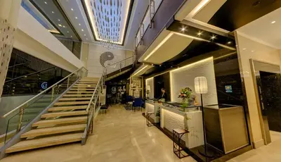 a lobby of a building with a staircase and a person at Y2 Residence Hotel Managed by HII in Manila