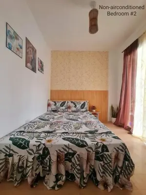 a bedroom with a bed with a comforter on it at Muji-inspired Home, 2-BR Bungalow Home Trece Martires in Trece Martires