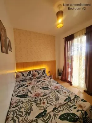 a bedroom with a bed with a floral bedspread at Muji-inspired Home, 2-BR Bungalow Home Trece Martires in Trece Martires