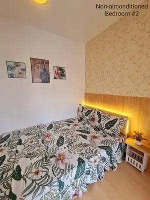 a bedroom with a bed with a floral bedspread at Muji-inspired Home, 2-BR Bungalow Home Trece Martires in Trece Martires