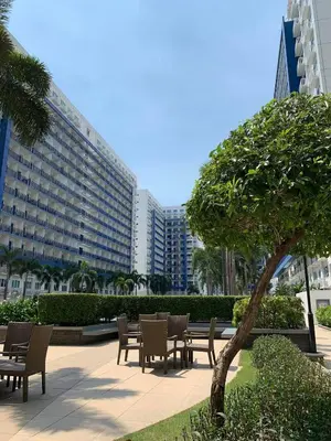 a group of tables and chairs in a park with a building at Wind and Sea at Sea Residences in Manila