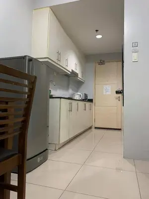 a kitchen with white cabinets and a door to a room at Wind and Sea at Sea Residences in Manila