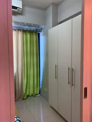 a room with a green curtain and a window at Wind and Sea at Sea Residences in Manila