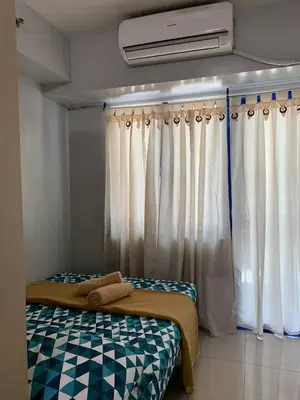 a bedroom with a bed and curtains and a heater at Wind and Sea at Sea Residences in Manila