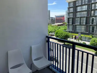 two white chairs sitting on a balcony with a building at Wind and Sea at Sea Residences in Manila