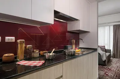 a kitchen with a counter top and a red wall at Somerset Central Salcedo Makati in Manila