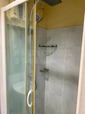 a shower with a glass door in a bathroom at Sea Residences by JH & LD's Condotel in Manila