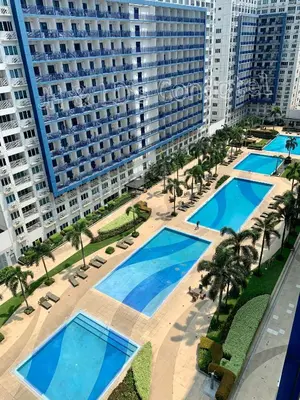 an overhead view of a pool with palm trees and buildings at Sea Residences by JH & LD's Condotel in Manila