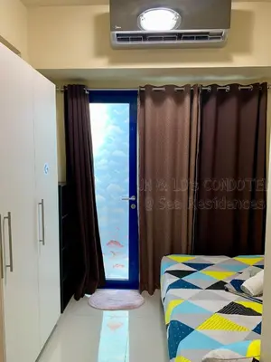 a bedroom with a window with a view of the ocean at Sea Residences by JH & LD's Condotel in Manila