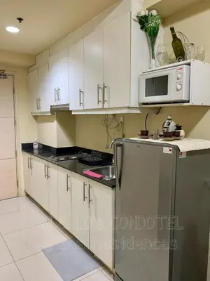 a kitchen with white cabinets and a stainless steel refrigerator at Sea Residences by JH & LD's Condotel in Manila