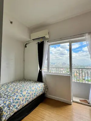 a bedroom with a bed and a large window at Taguig City Grace Residences with small balcony in Manila